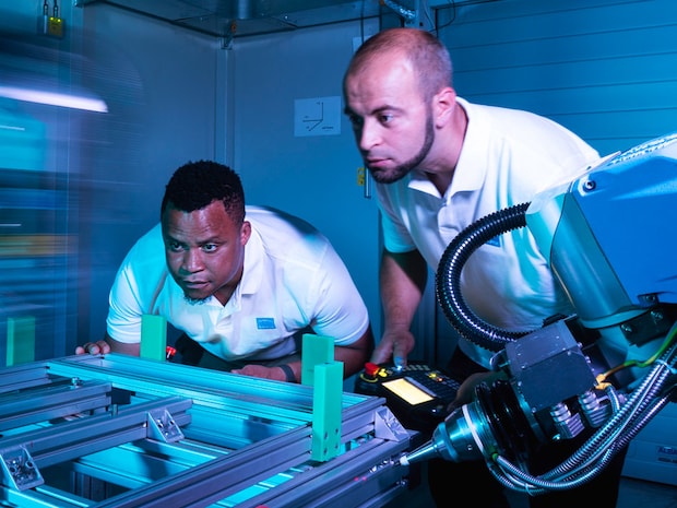 Two employees work on a machine
